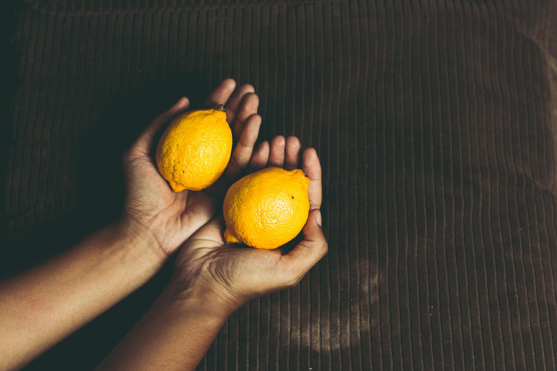 Close-up of a hand selecting from a curated collection of colorful lemon sexual toys on a black display tray