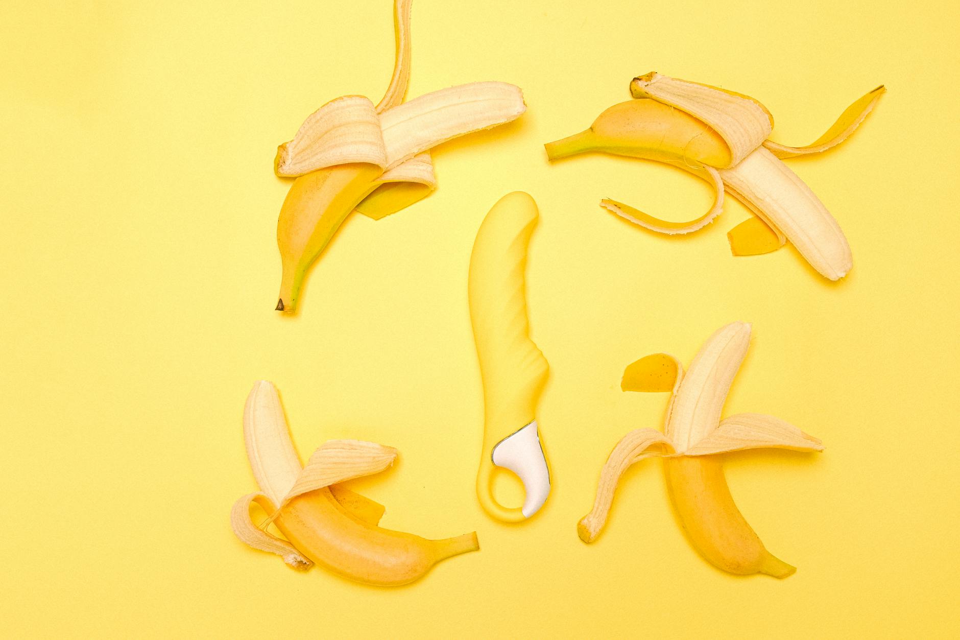 Yellow lemon clitoral vibrator with fresh lemons on bright yellow background