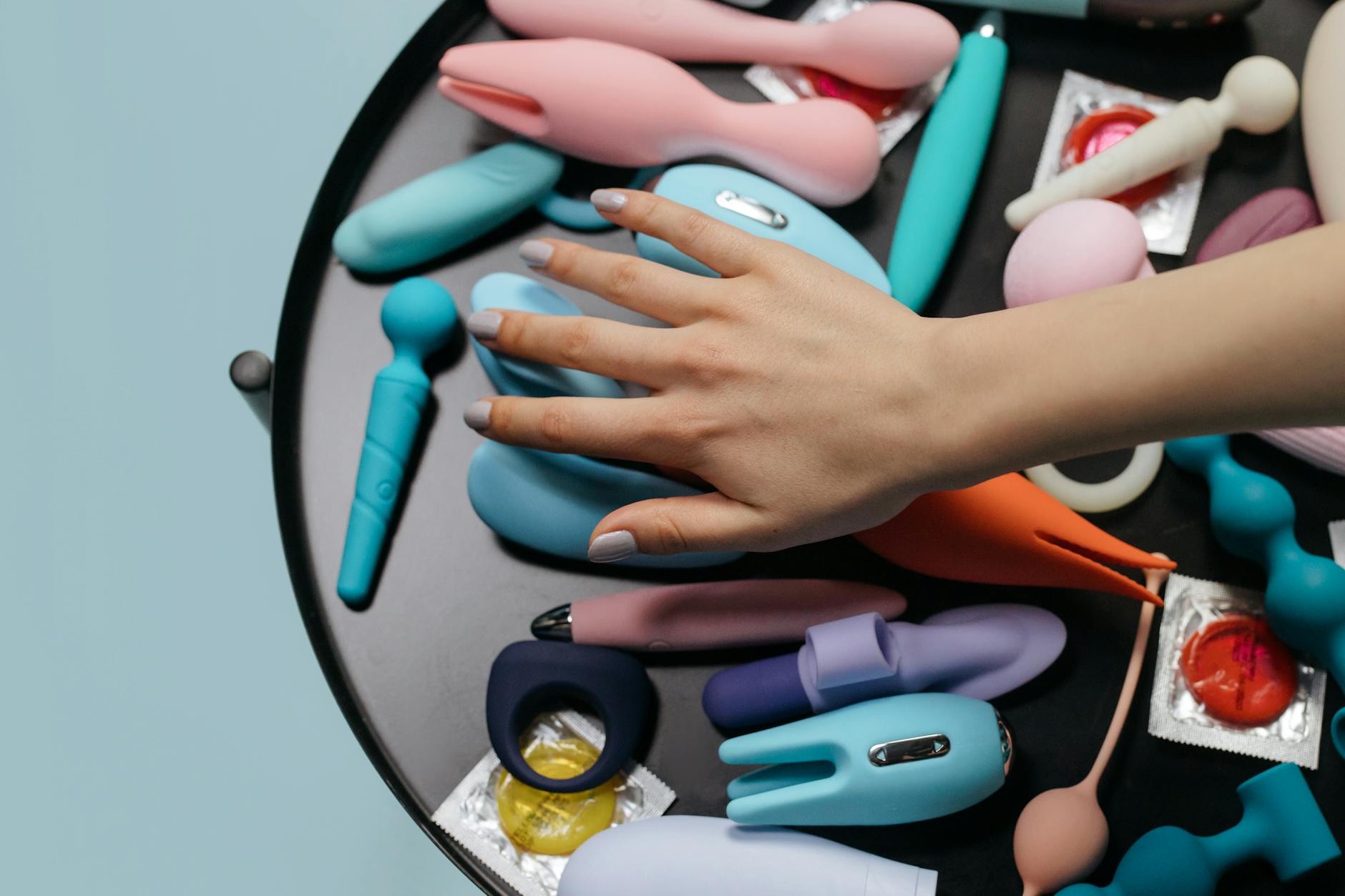 Two hands holding pastel silicone toys together, representing shared exploration and intimacy between partners.