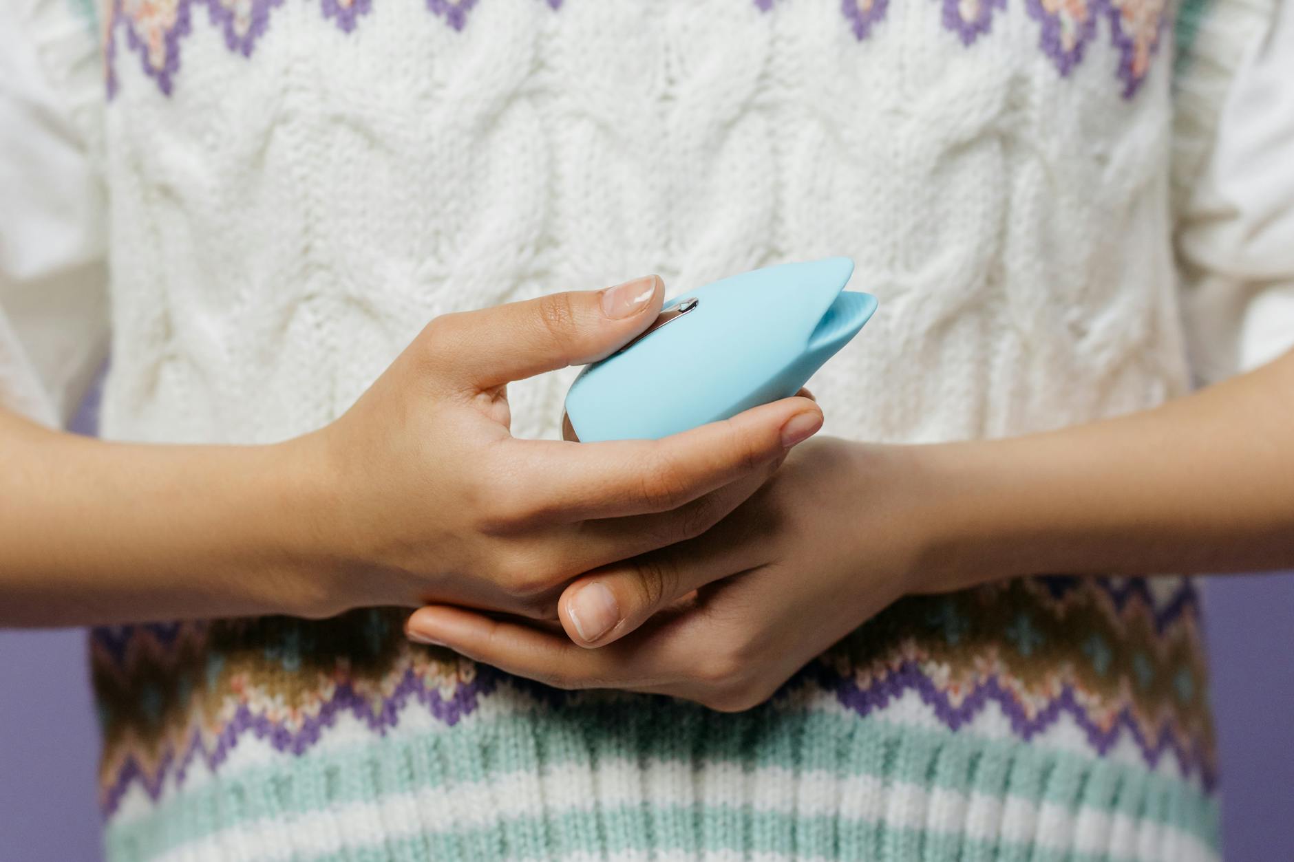 A blue silicone sex toy held in hand against a purple background, promoting self-love and sexuality.