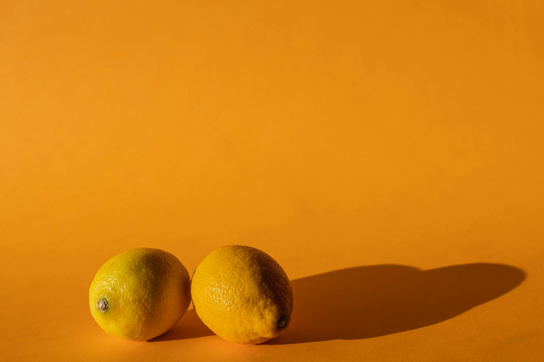 Bright yellow lemons arranged on a pastel green background